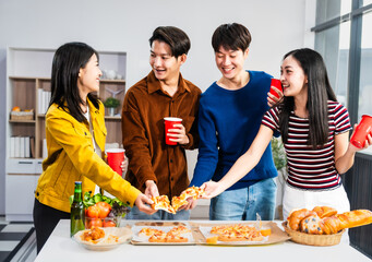 .Young Asian students gather with friends for a pizza party, laughing and sharing slices. Enjoying fast food delivery, they embody diversity and togetherness in a relaxed, enjoyable lifestyle.