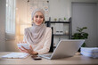 Young Muslim businesswoman holds a meeting over the phone and calculates company finances on her work desk.