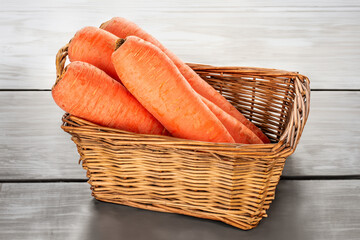 Wall Mural - Peeled sweet carrots in a basket on a wooden table.