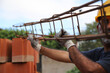 Builder working on construction site. Professional bricklayer working on house construction. Concept of architecture, industry. Construction worker carrying an iron beam at a construction site.