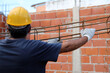 Construction worker carrying an iron beam at a construction site. Builder working on construction site. Professional bricklayer working on house construction. Concept of architecture, industry.