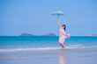 Happy sexy Asian traveller woman wear colorful beach dress umbrella and hat  show enjoys on tropical beach vacation in summer holidays	
