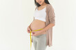 Pregnant woman using measuring tape to check size of belly pregnancy and baby development