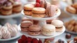 An elegant presentation of a tiered dessert stand with assorted petit fours and macarons.