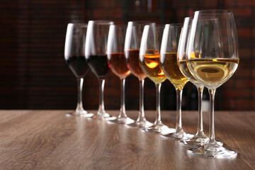 Wall Mural - Different tasty wines in glasses on wooden table