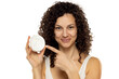 Portrait of an attractive young woman holding a beauty product against a white background.