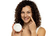 Portrait of an attractive young woman apply a beauty product on her face against a white background.
