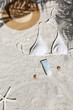 Broad brim straw hat, white bathing suit bra and sunblock tubes. Top view, flat lay, copy space, background.