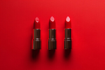 red lipstick on a vivid red background with copy space. cosmetics banner concept, top view, flat lay