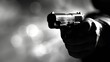   A monochrome image of an individual aiming a firearm at the lens against a backdrop of indistinct, glowing lights