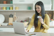 Young woman shopping on-line.  young woman using her card and phone to shop online at home.