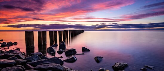 Wall Mural - A serene coastal sunset with rocks and a pier