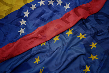 waving colorful flag of european union and flag of venezuela on a euro money banknotes background. finance concept.