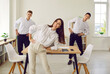 © Studio Romantic - Happy business team having sports workout in office. Group of three fit corporate employees doing fitness exercises together. Happy young woman and two men standing in office doing side bend exercise