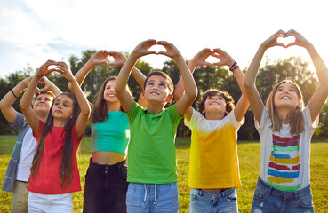 happy children making heart shapes with their hands raised. group of smiling boys and girls playing 