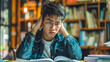 © Napat.T - A young man is sitting at a table with a book in front of him