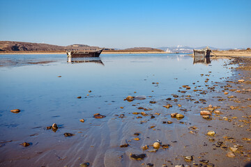 Wall Mural - An abandoned Korean fishing boat washed ashore during a storm. An old fishing schooner washed up in shallow water during a storm.