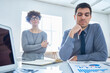 © Mediaphotos - Front view portrait of adult man looking at charts in office with colleague in background