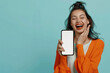 A gleeful young woman stands beside a blank mobile phone screen, her vibrant energy complementing the pastel blue setting