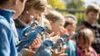 A crowd of delighted pupils examining and handling blue baby parrots in a school aviary setting. It is a close-range shot on a brilliant sunny day. 
