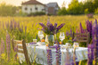 Beautiful romantic outdoor wedding decor in a field. Table decorated with purple lupines flowers. Wineglasses with white wine. Sunset, summer, golden hour. Perfect surprise date for loving couple