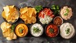 A variety of dips and chips are spread out on the table