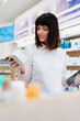 Beautiful pharmacist working and standing in a drug store and doing a stock take. Portrait of a positive healthcare worker or a chemist at his work.