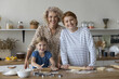 Intergenerational bonding, culinary traditions. Two generations of women and little girl cook, pose for camera, enjoy cookery, warm relations, creating lasting memories and connection through cooking