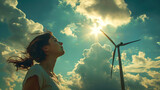 Fototapeta  - a girl looking up at a wind turbine in the sky with clouds in the background and a sun shining through the clouds