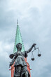 statue of lady justice under cloudy sky with church tower