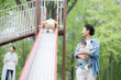 新緑の公園の滑り台で遊ぶアジア人（日本人）の親子 4人家族　子育てや育児の休日のイメージ	