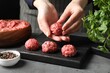 Woman making meatball from ground meat at grey table, closeup