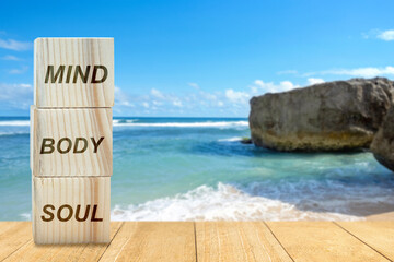 Stack of small wooden cubes with the text of mind, body, and soul on the table