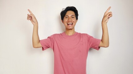 Wall Mural - excited young handsome asian man happy, cheerful and excited posing pointing to the top side with isolated white background