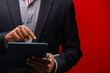 Close up hands of businessman using digital tablet device isolated on red background.