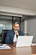© insta_photos - Busy older serious middle aged business man sitting at desk using computer. Mature businessman executive wearing shirt and glasses working looking at computer technology in office. Vertical photo.