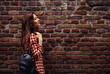 Portrait of the cute teen girl in casual clothing thinking and looking on red old brick wall pattern banner natural building background. Empty space for text.