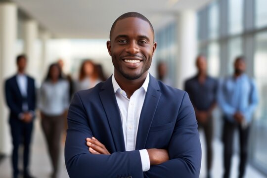 Smiling confident african businessman looking at camera and standing in an office at team meeting smiling adult happiness.