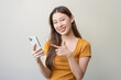 Young Asian female showing screen of mobile and thumb up to guarantee.