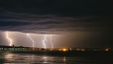 Fototapeta  - lightning over the city, Bright lightning strikes the ground at night. Stormy sky with multiple lightning from the clouds over the sea against the backdrop of the night city