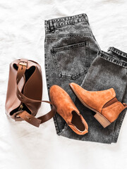 Wall Mural - Women's grey mom jeans, brown leather tote bag, suede chelsea boots on a light background, top view