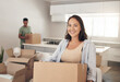 © peopleimages.com - Happy woman, moving and carry box in new house for property, investment and real estate in living room. Female homeowner, smile and joy in apartment for immigration and relocate or home purchase