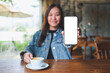 Mockup image of a woman showing a mobile phone with blank white screen in cafe