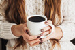 Hot coffee in a mug. Woman holding mug of dark coffee. Cold winter relax background. Woolen sweater warm clothing. Long hair girl. Cozy atmosphere. Female hands holding americano cup.