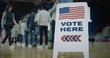 © Framestock - Vote here sign on the floor. Queue of multi ethnic American citizens come to vote in polling station. National Election Day in United States. Political races of US presidential candidates. Civic duty.