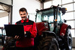 Professional serviceman holding diagnostic tool and servicing tractor.