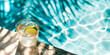 cocktail glass with a slice of green lime inside next to a swimming pool