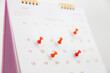 Red pin on blank desk calendar in office workplace concept time management event planner or personal organization for business meeting and appointment reminder and schedule planning or holiday plan.
