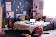 No people wide shot of modern teenagers bedroom interior with laptop on bed, posters and lights on walls, copy space