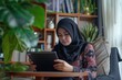 Happy young Muslim woman in Indonesia on phone at home.